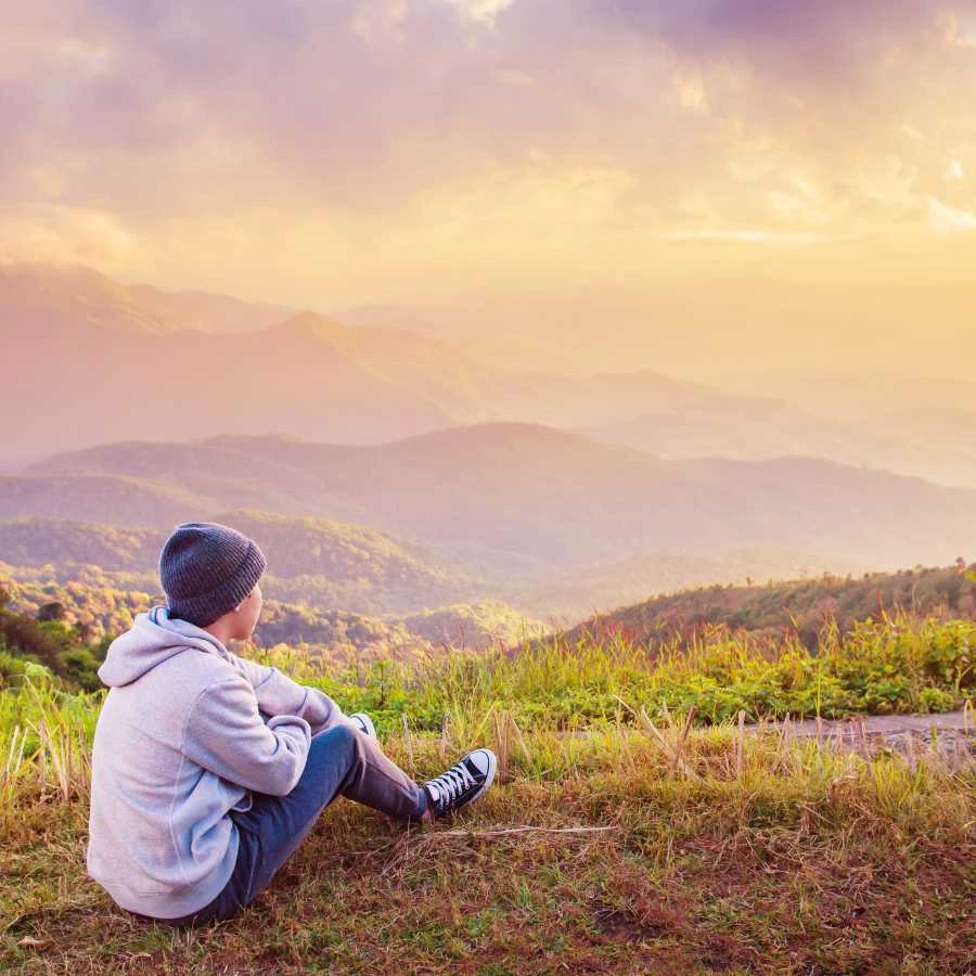 Persona seduta al tramonto che contempla un paesaggio montano silenzioso