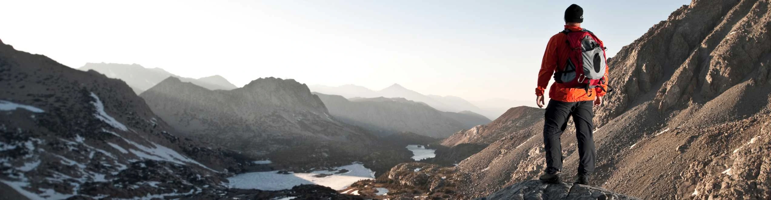 Viaggiatore in montagna che osserva il panorama al tramonto durante un viaggio esperienziale