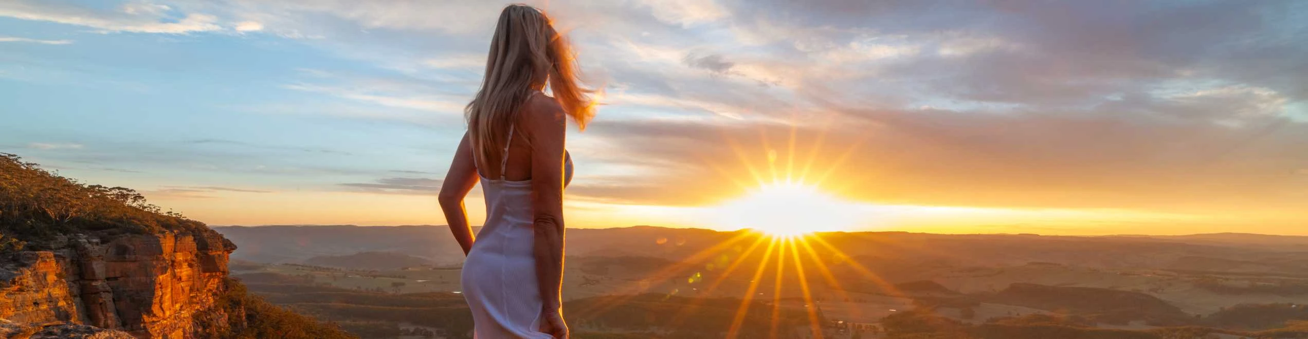 Persona che osserva il tramonto da una scogliera panoramica in una destinazione tranquilla