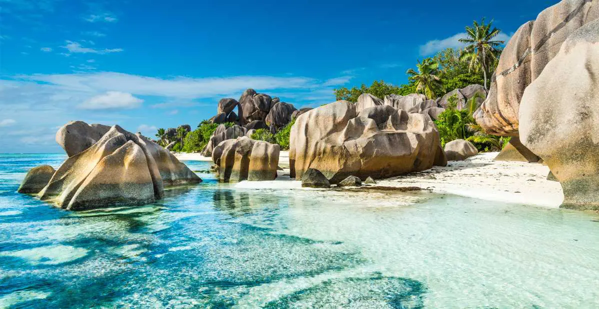 Spiaggia paradisiaca alle Seychelles con sabbia bianca, acqua cristallina e formazioni rocciose granitiche uniche.