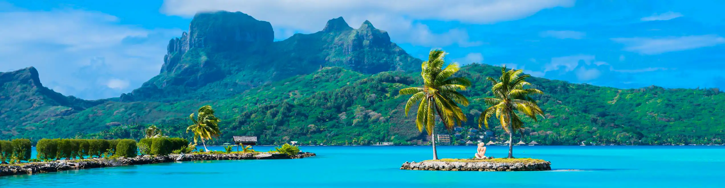 Isolotto tropicale con palme circondato da acque turchesi a Bora Bora, Polinesia Francese.