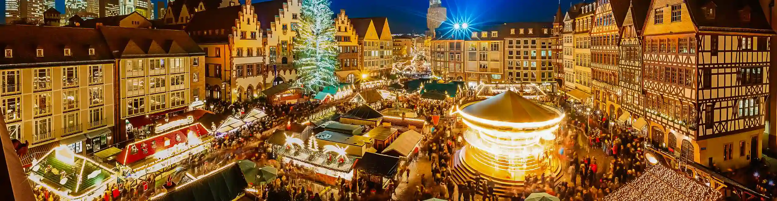 Mercatino di Natale illuminato nella piazza centrale di Francoforte, con grande albero decorato e palazzi storici