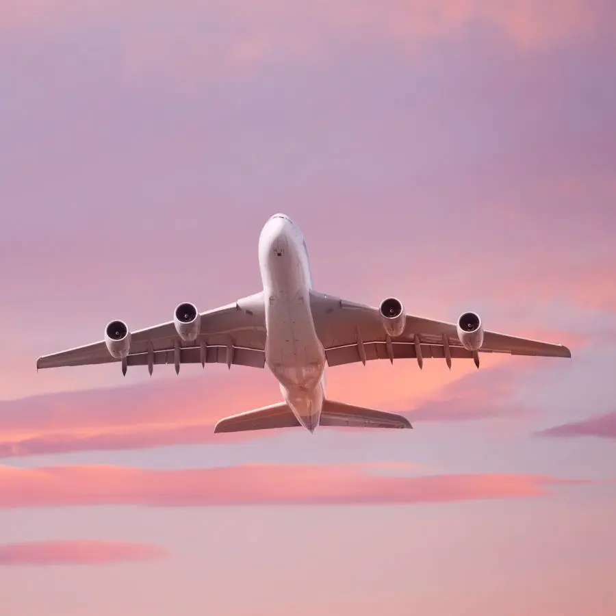 Viaggiatore di spalle con le braccia aperte davanti a un vulcano innevato e paesaggio montano