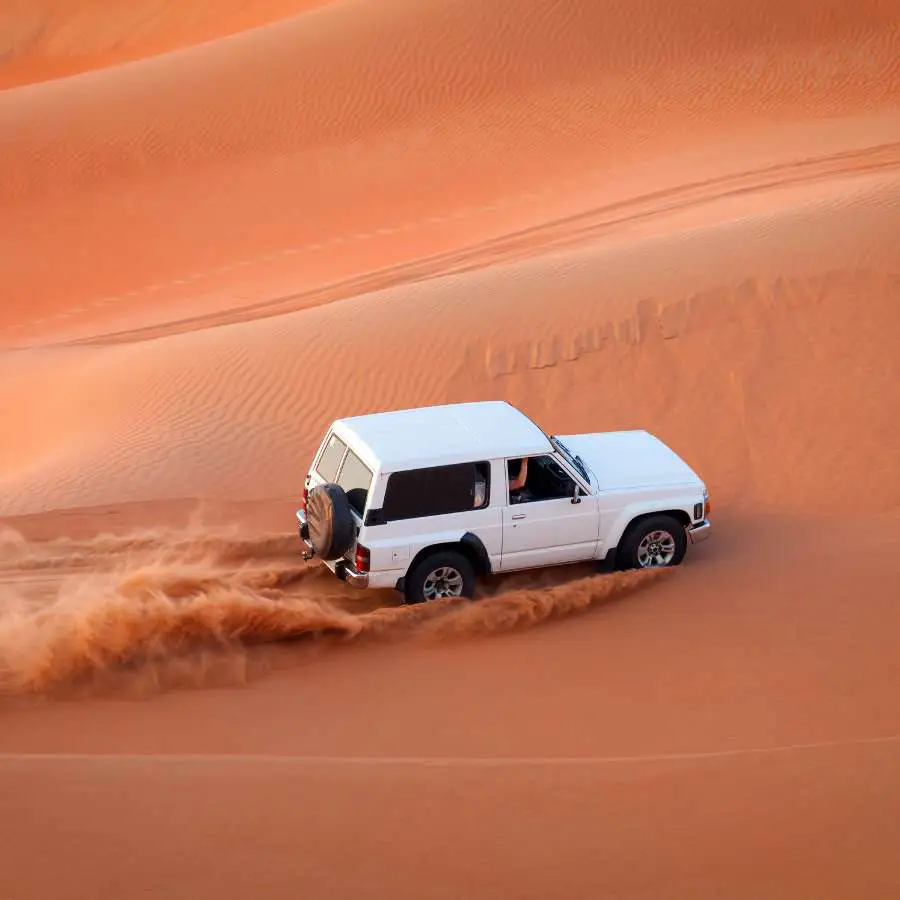 Viaggiatori esplorano una formazione rocciosa nel deserto della Namibia al tramonto</p>
<p>