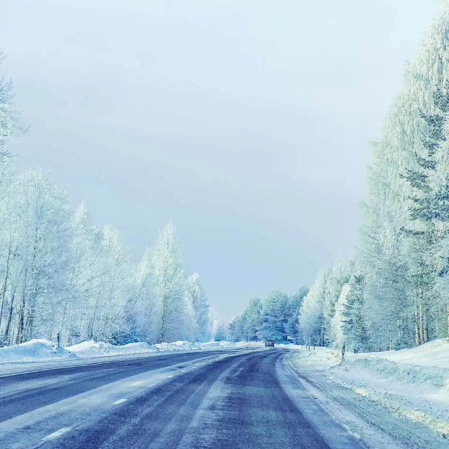Viaggiatore di spalle con le braccia aperte davanti a un vulcano innevato e paesaggio montano