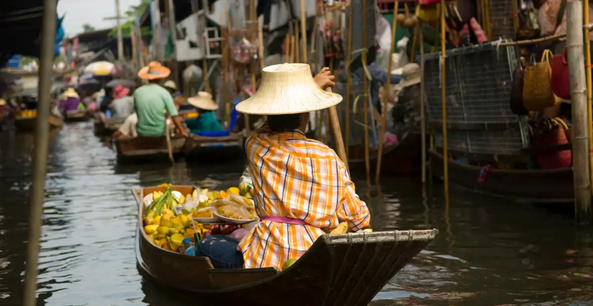 Venditrice in barca al mercato galleggiante thailandese, tra canali e vita quotidiana, simbolo della Thailandia autentica.