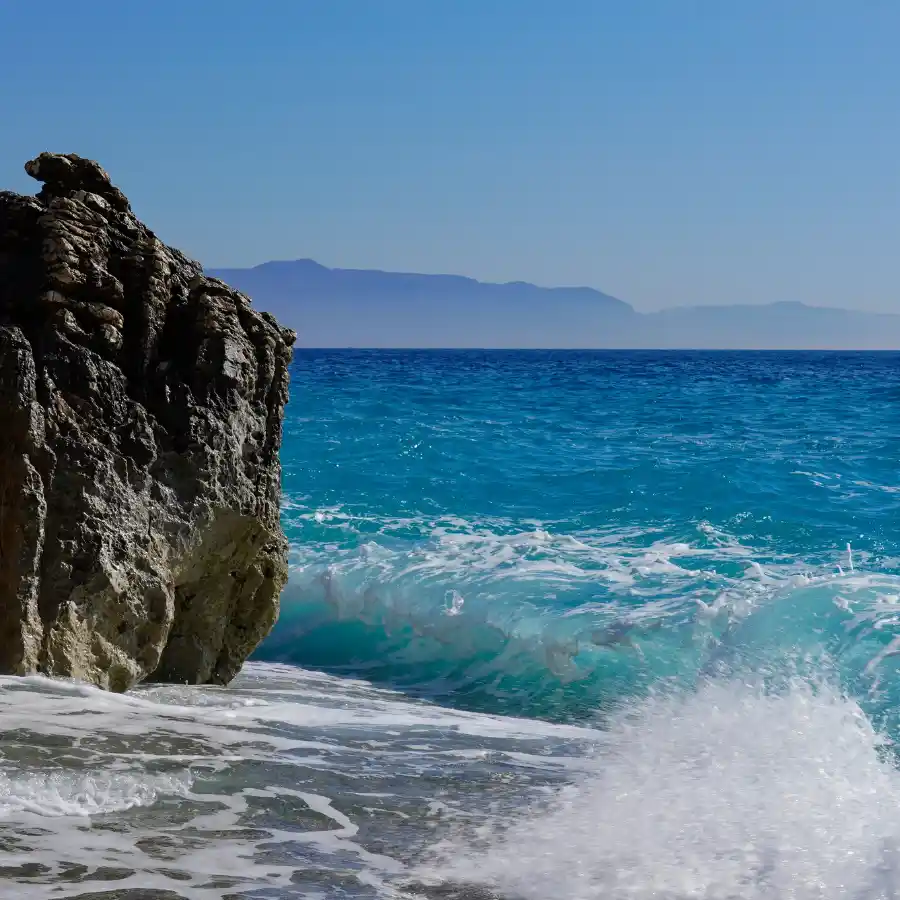 Onda sul mare cristallino con scogliera lungo la costa dell’Albania sotto cielo limpido