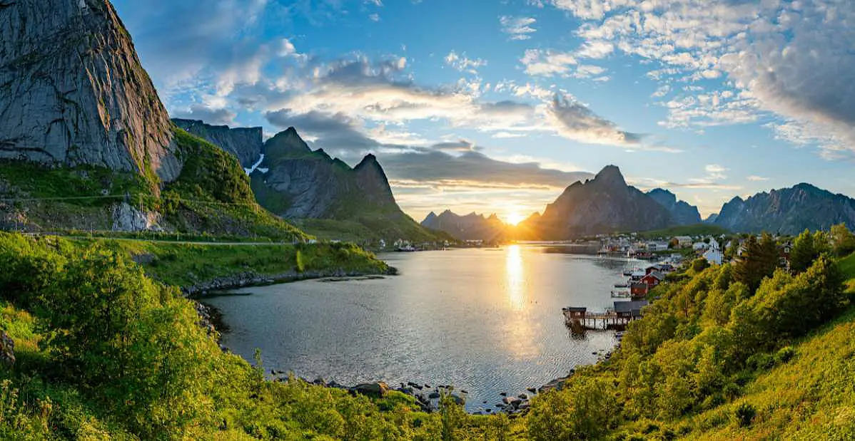 Paesaggio dei fiordi norvegesi al tramonto con montagne, villaggio sul mare e natura incontaminata