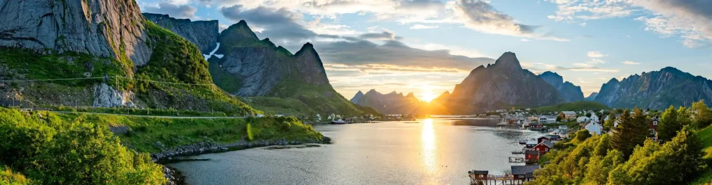Fiordo norvegese al tramonto con villaggio sul mare e montagne spettacolari lungo la costa della Norvegia