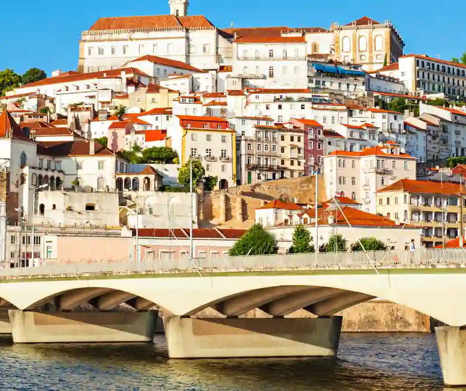 Offerta viaggio Portogallo Classico: viaggio organizzato tra Coimbra e città storiche Vista di Coimbra con case colorate, ponte sul fiume e centro storico su collina