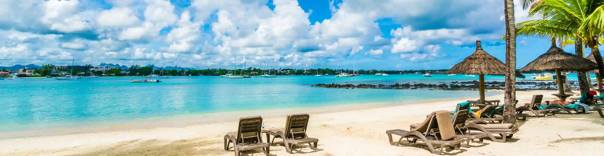 Spiaggia di Mauritius con palme, lettini, ombrelloni e mare turchese sotto un cielo luminoso