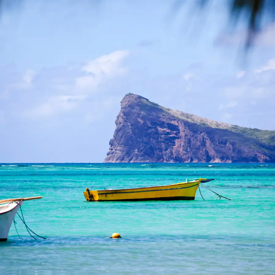 Barca nella laguna turchese di Mauritius con mare cristallino e montagna sullo sfondo