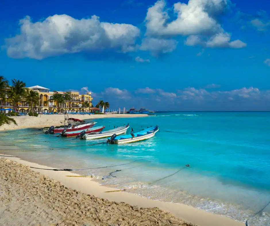 Offerta viaggio Riviera Maya mare e relax Caraibi Barche sulla spiaggia della Riviera Maya con mare turchese e resort sullo sfondo