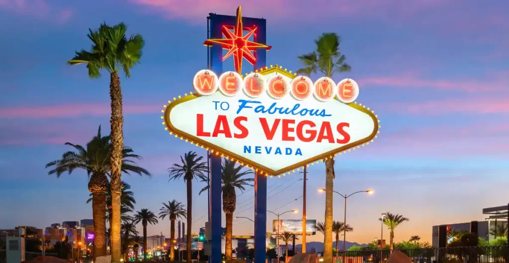 Insegna Welcome to Fabulous Las Vegas al tramonto con palme e luci della città