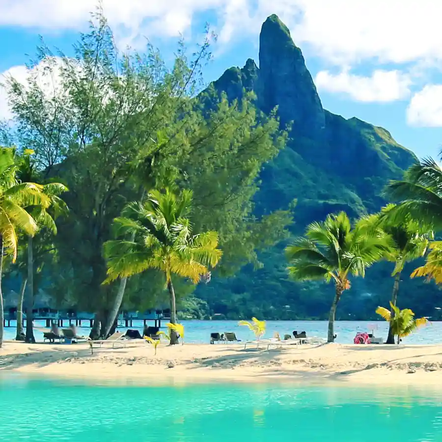 Spiaggia tropicale a Bora Bora con laguna turchese e montagne della Polinesia