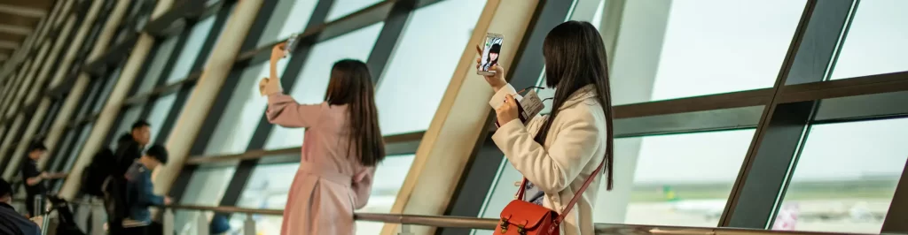 Turista in aeroporto utilizza lo smartphone prima della partenza grazie a una eSIM per viaggi.