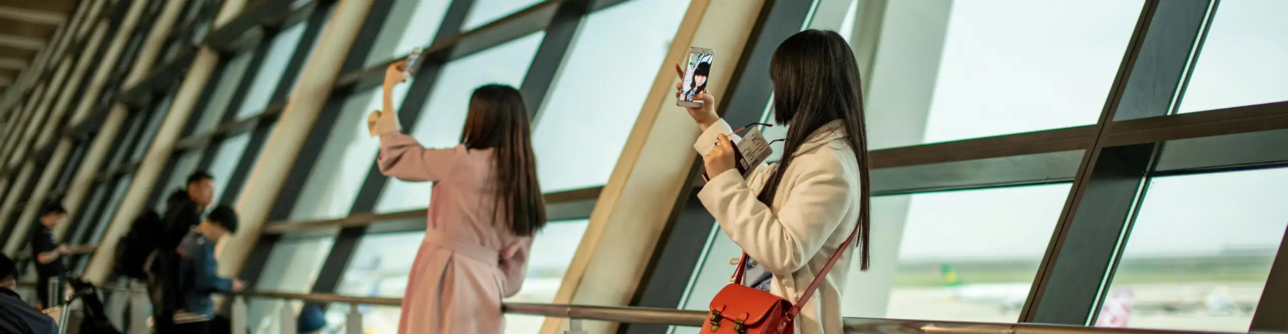 Turista in aeroporto utilizza lo smartphone prima della partenza grazie a una eSIM per viaggi.