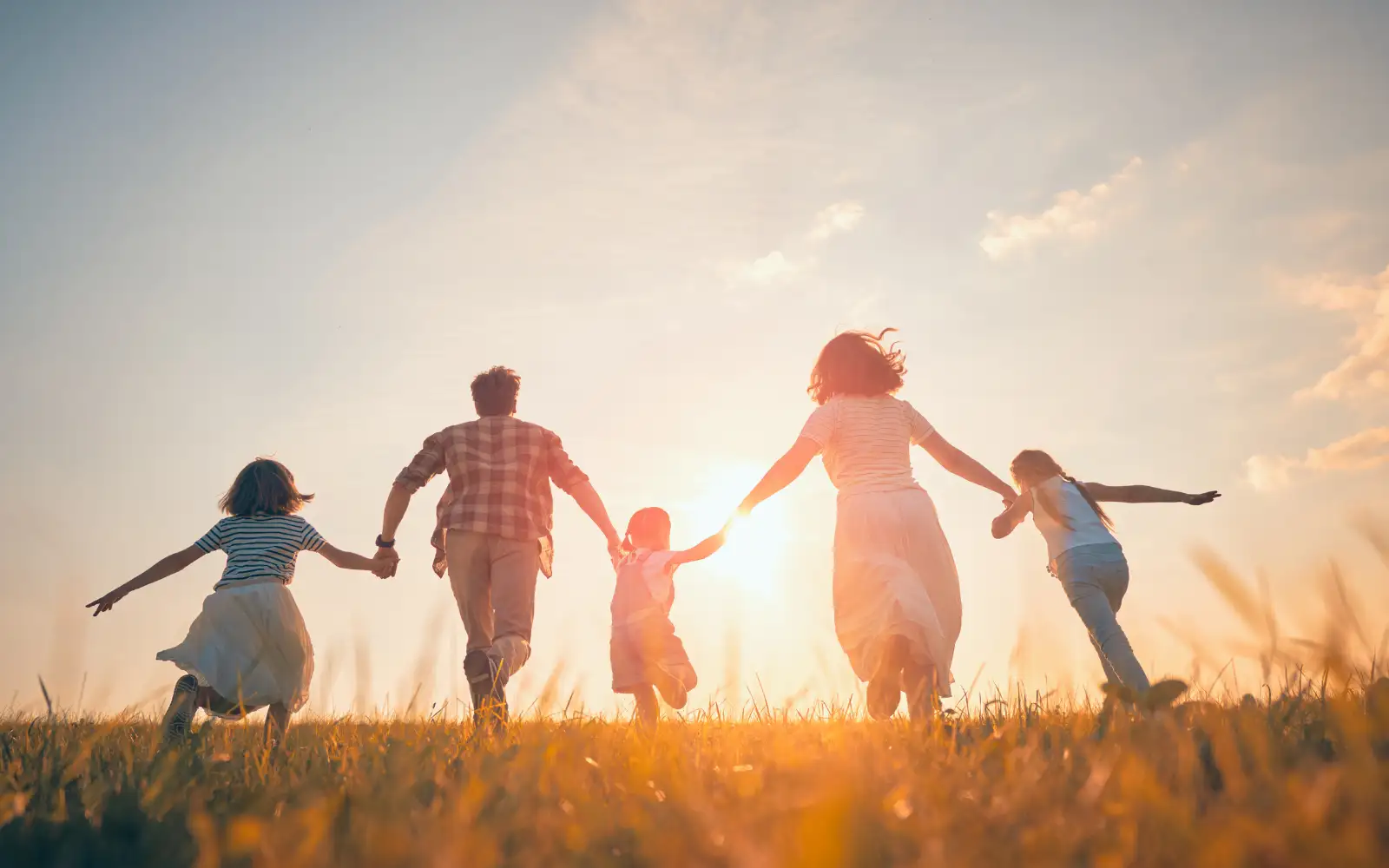Famiglia corre in un prato al tramonto durante una giornata all'aperto