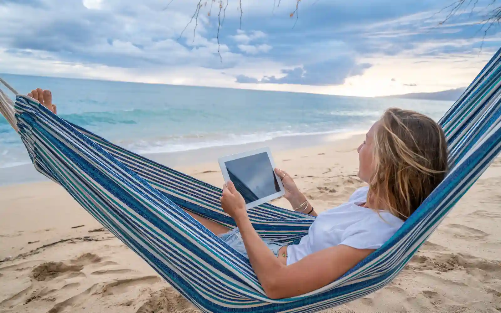 Donna in relax sulla spiaggia mentre utilizza una connessione eSIM durante il viaggio