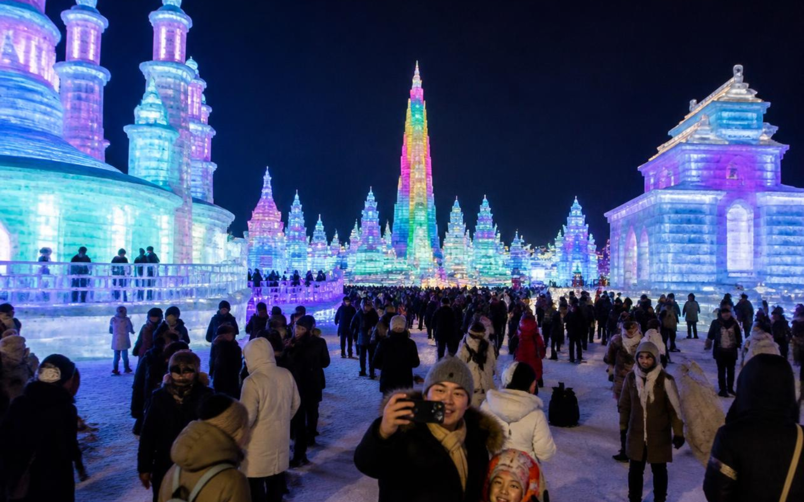 Visitatori passeggiano tra le costruzioni illuminate del Festival del Ghiaccio di Harbin