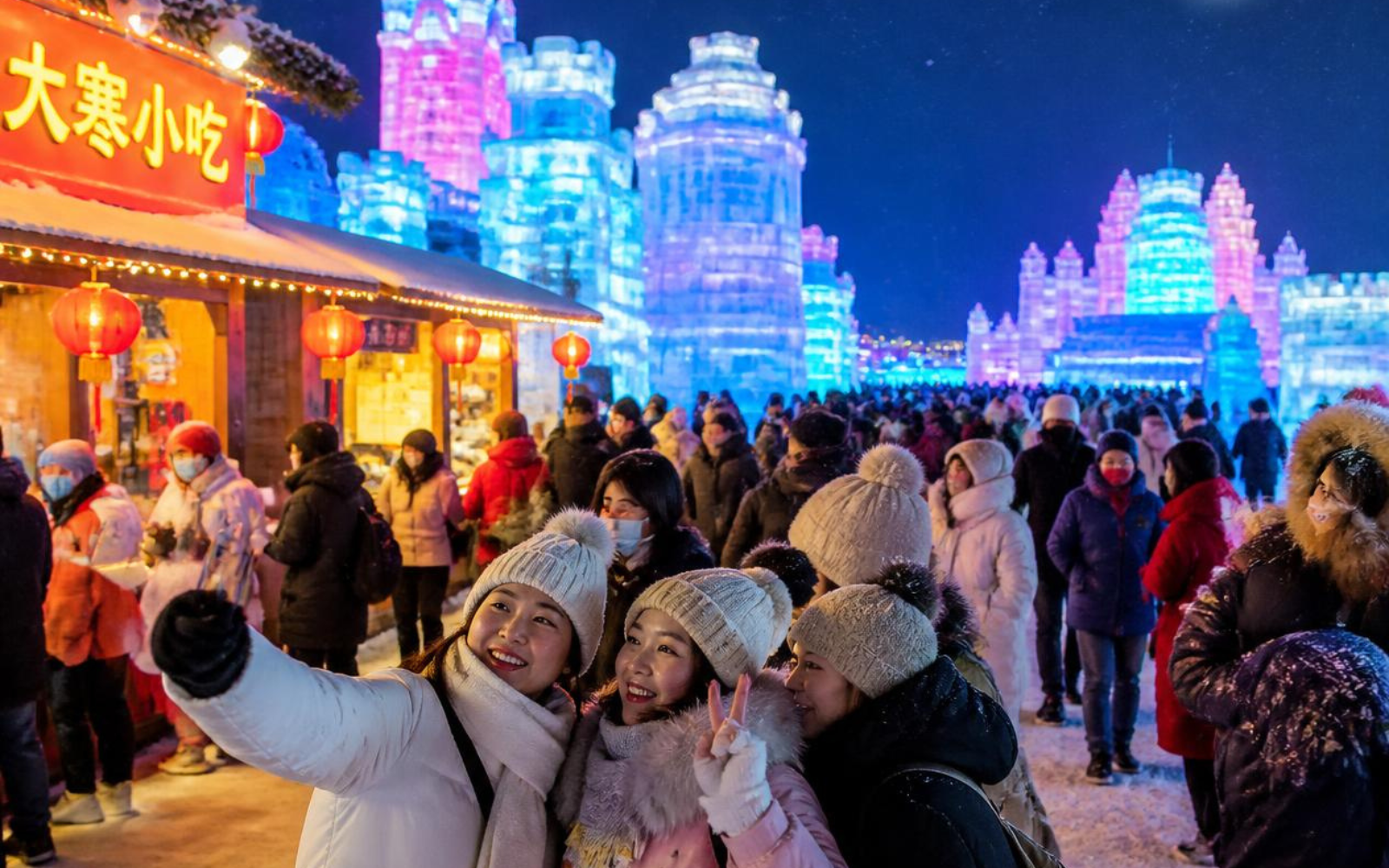 Visitatori ben coperti tra le luci del Festival del Ghiaccio di Harbin