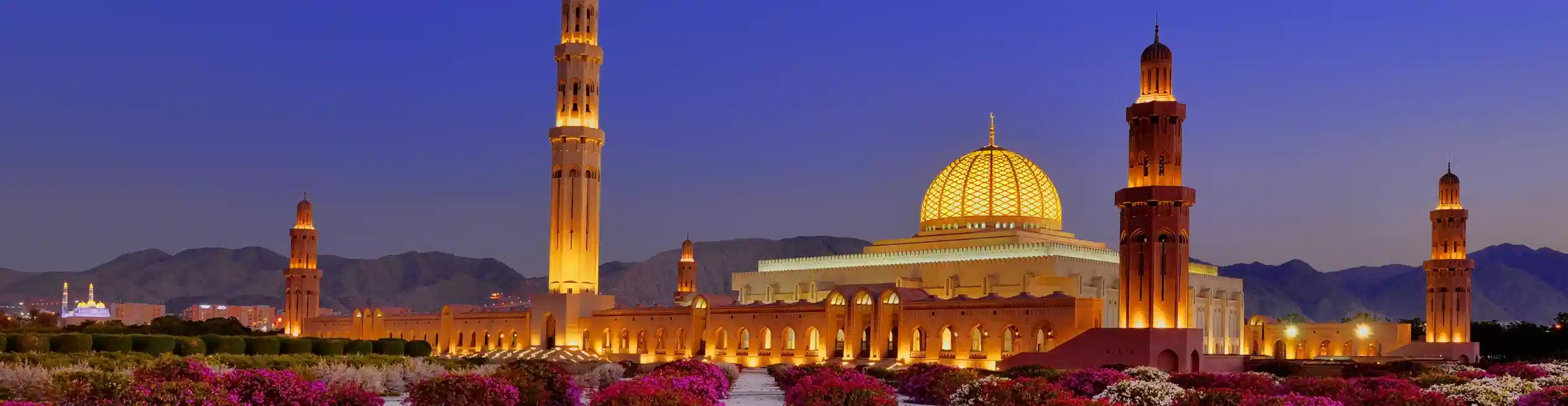 Grande Moschea del Sultano Qaboos illuminata al tramonto a Muscat, in Oman.