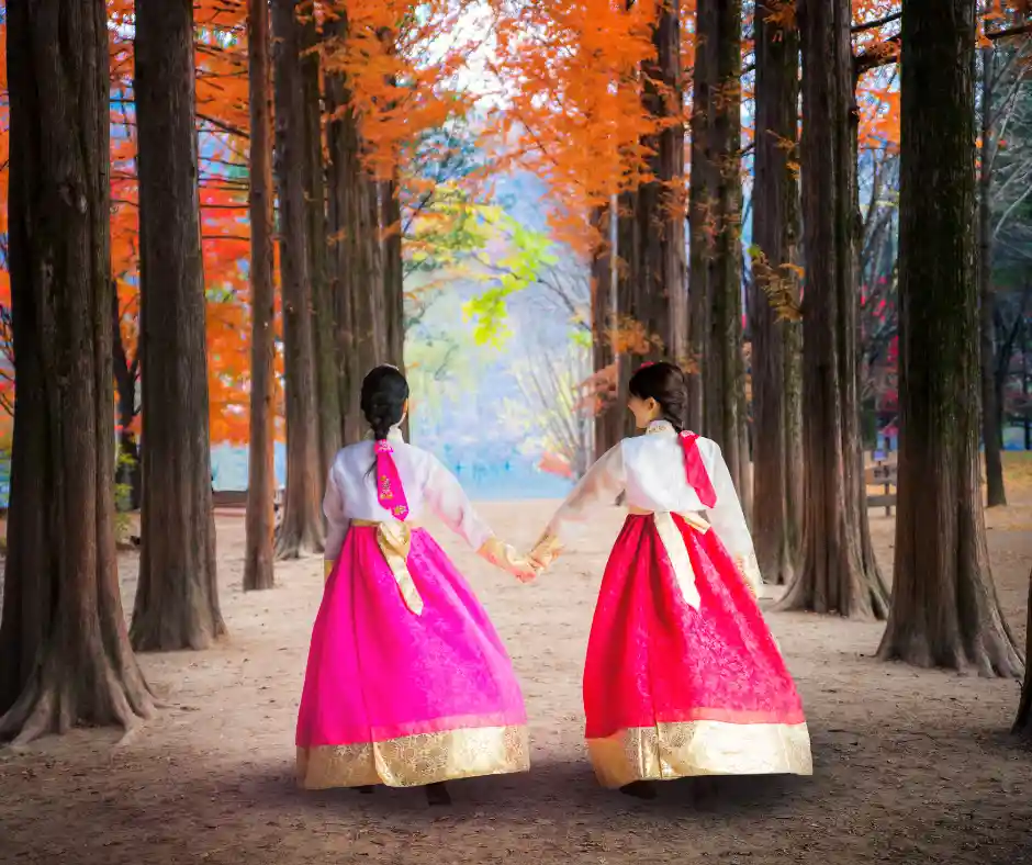 Offerta viaggio Corea del Sud tra tradizioni, natura e cultura Due donne in abito tradizionale hanbok passeggiano in un viale alberato durante l'autunno in Corea del Sud.