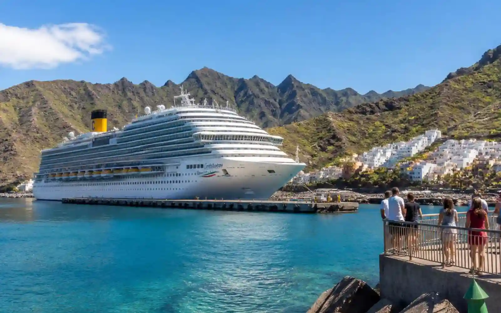 Nave Costa Crociere attraccata davanti a una località costiera tra mare e montagne