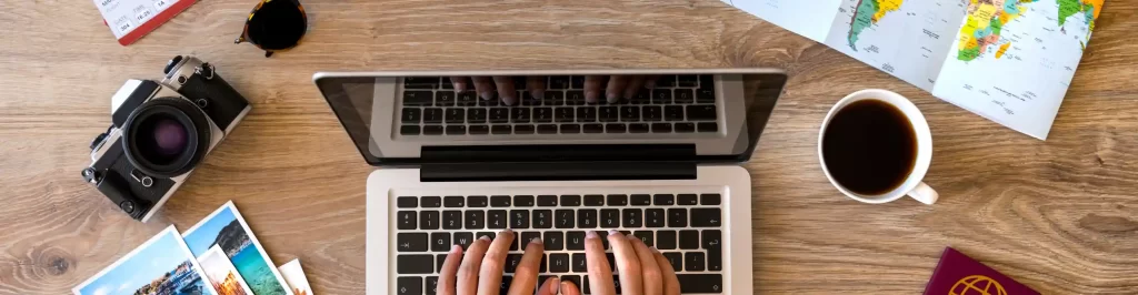 Persona organizza una vacanza al computer con mappe e accessori da viaggio