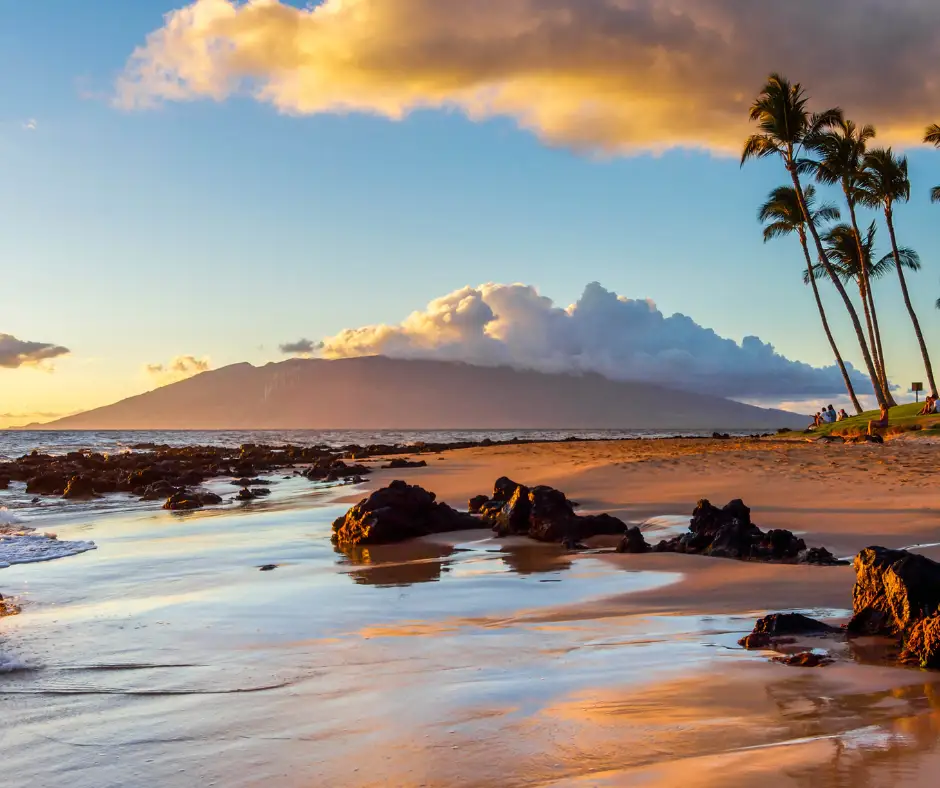 Pacchetto vacanza Hawaii – Tramonto a Maui Tramonto su una spiaggia di Maui con palme e oceano.