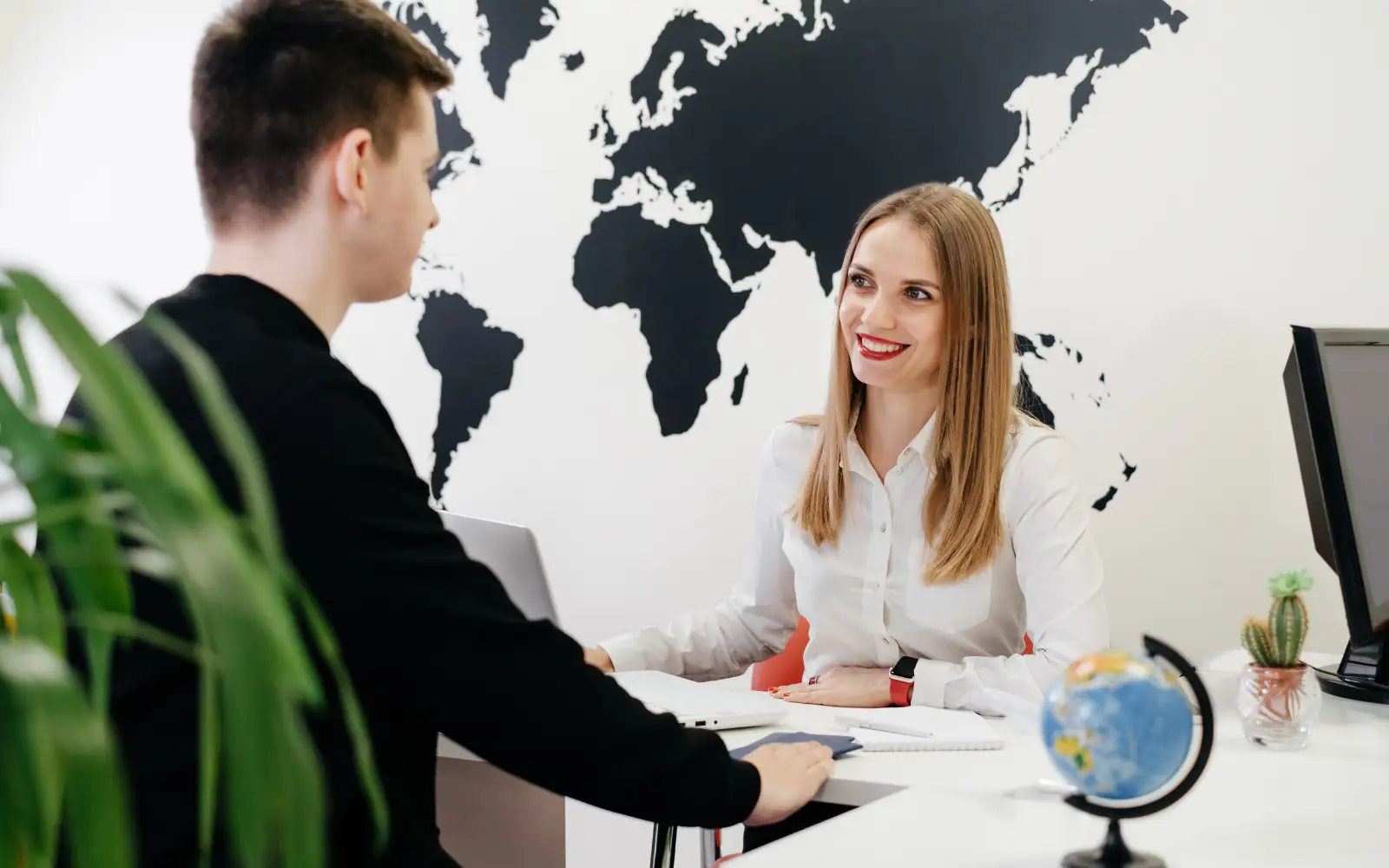 Consulente di viaggio parla con un cliente in ufficio durante la pianificazione di un viaggio