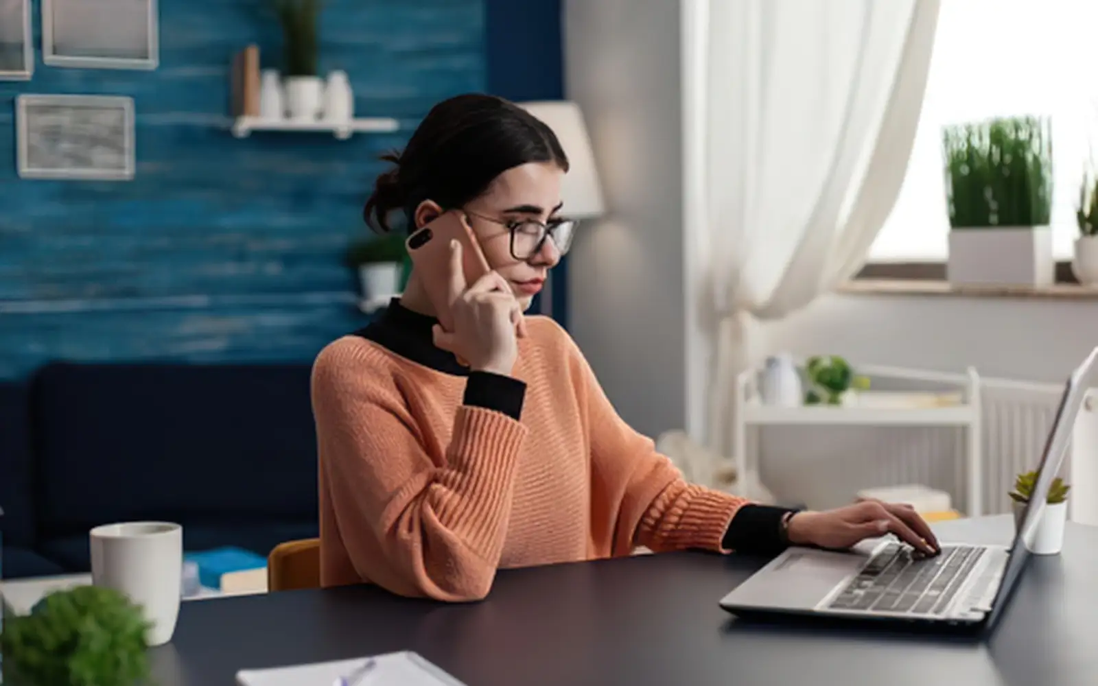 Donna al computer parla al telefono mentre controlla informazioni relative a una prenotazione