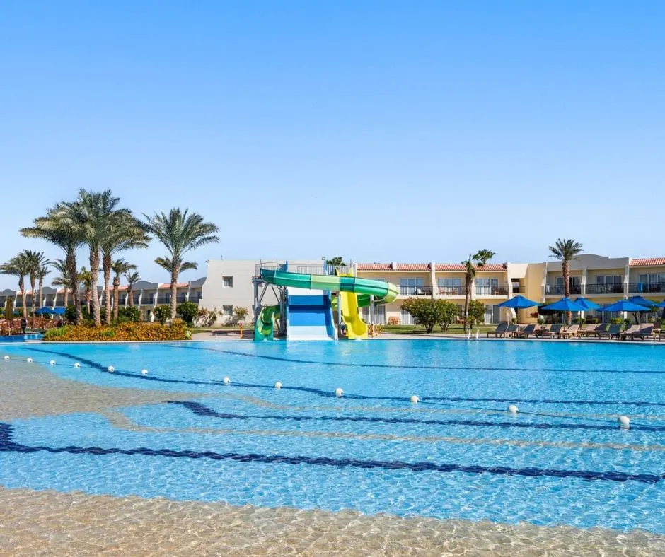 Piscina con scivoli a Sharm el-Sheikh Grande piscina con scivoli acquatici, palme e lettini nelle aree esterne del resort.