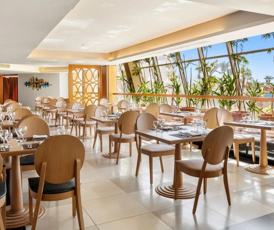 Ristorante del DoubleTree by Hilton Sharm Sala ristorante luminosa con tavoli apparecchiati e grandi finestre affacciate sul verde.