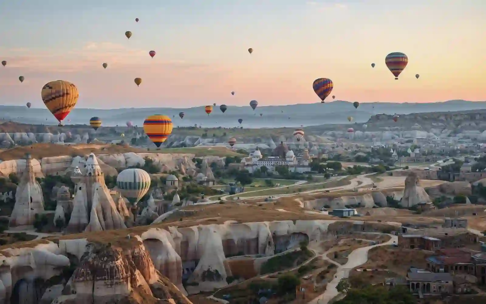 Numerose mongolfiere volano all'alba sopra le vallate e le formazioni rocciose della Cappadocia