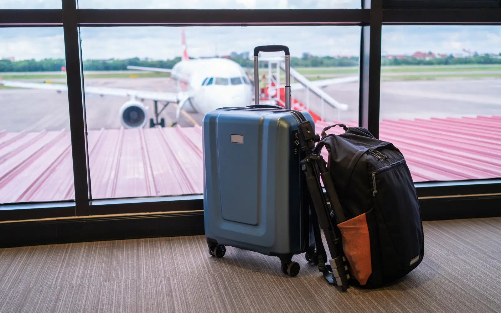 Valigia e borsa da viaggio davanti alla vetrata di un aeroporto con aereo sulla pista