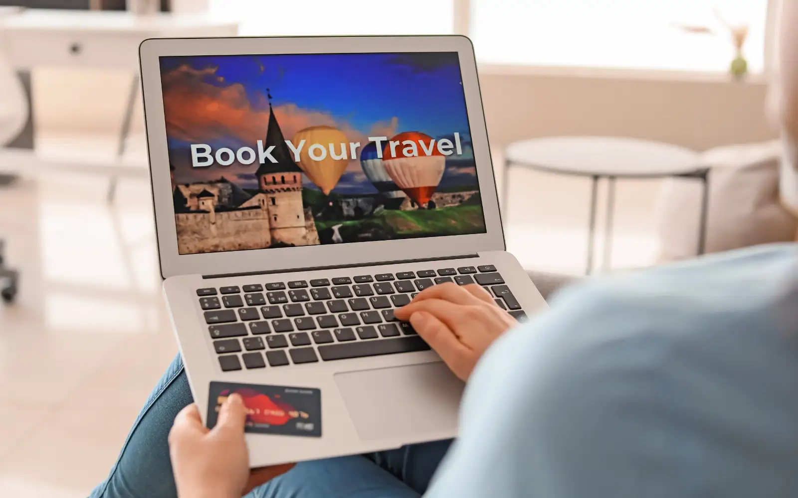 Persona prenota un viaggio online dal laptop tenendo una carta di pagamento