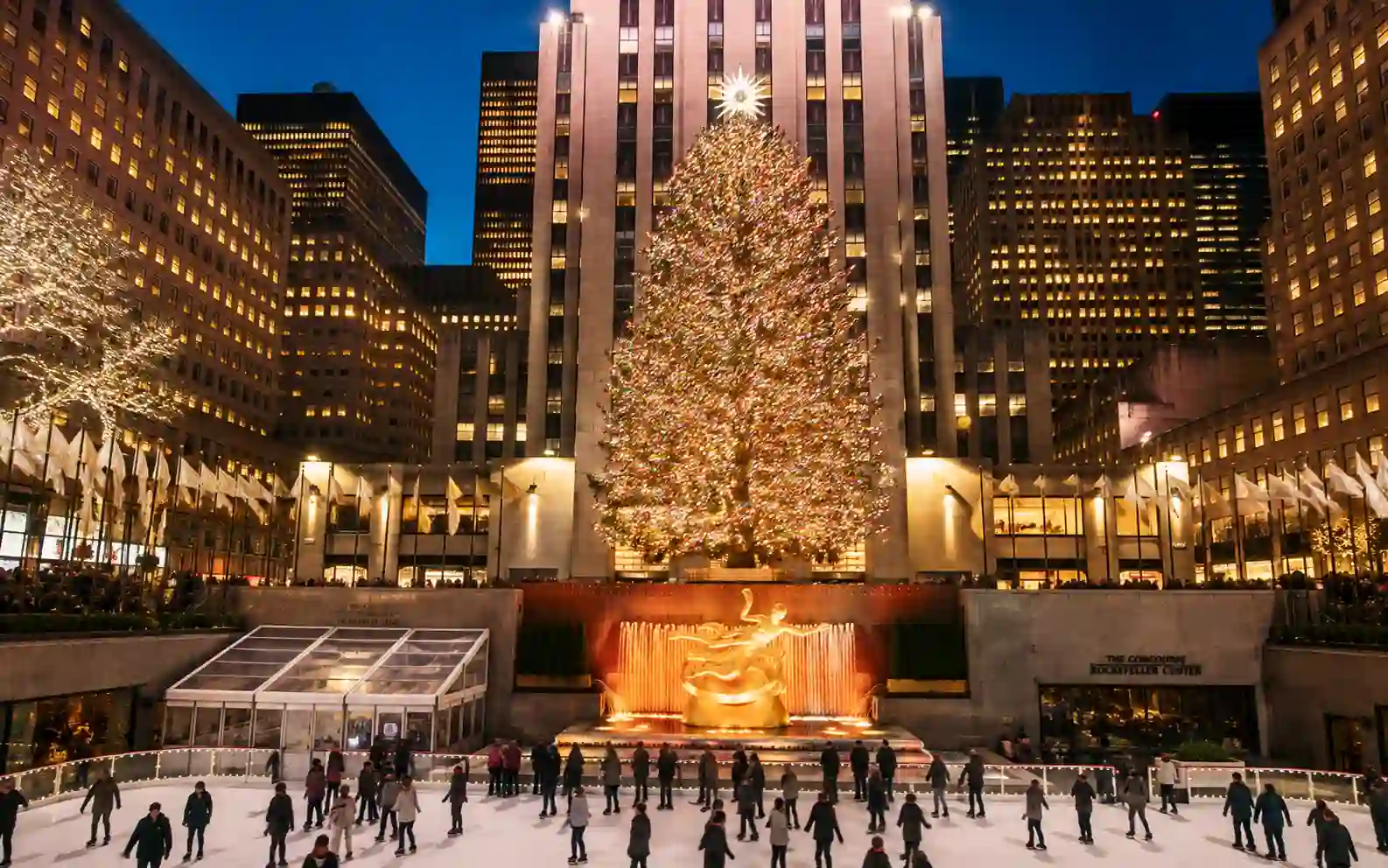 Albero di Natale illuminato e pista di pattinaggio al Rockefeller Center di New York durante la sera