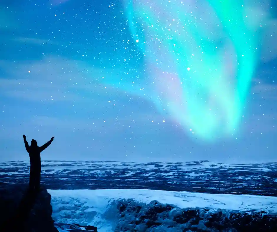 Aurora Boreale in Islanda Aurora boreale verde sopra un paesaggio innevato con una persona in primo piano.