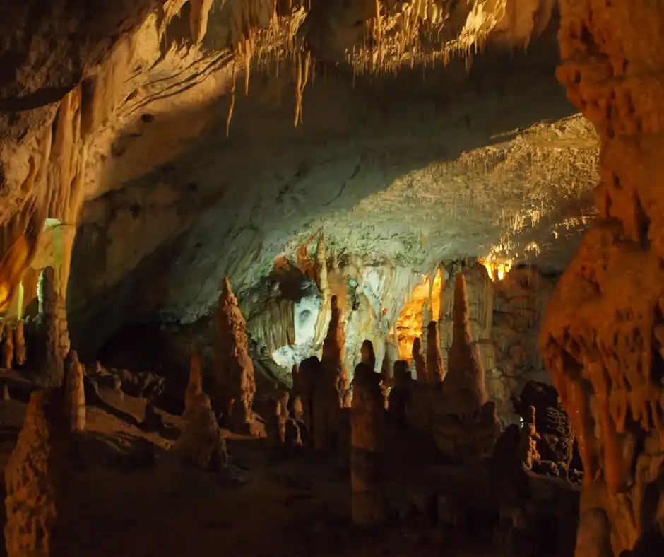 Nel cuore delle grotte slovene Interno di una grotta con stalattiti e stalagmiti illuminate.