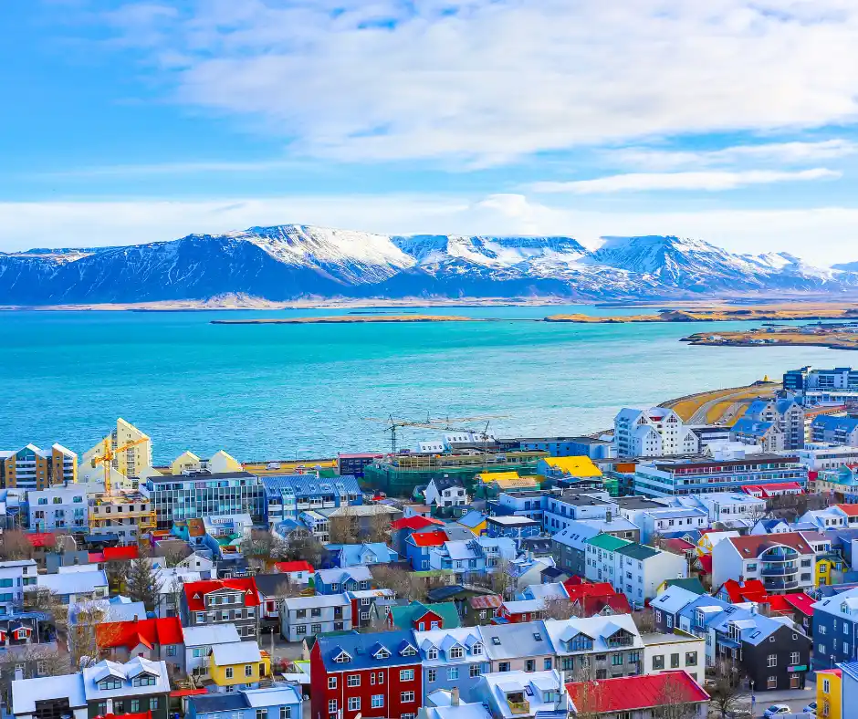Reykjavik in inverno Panorama invernale di Reykjavik con case colorate, mare e montagne innevate sullo sfondo.
