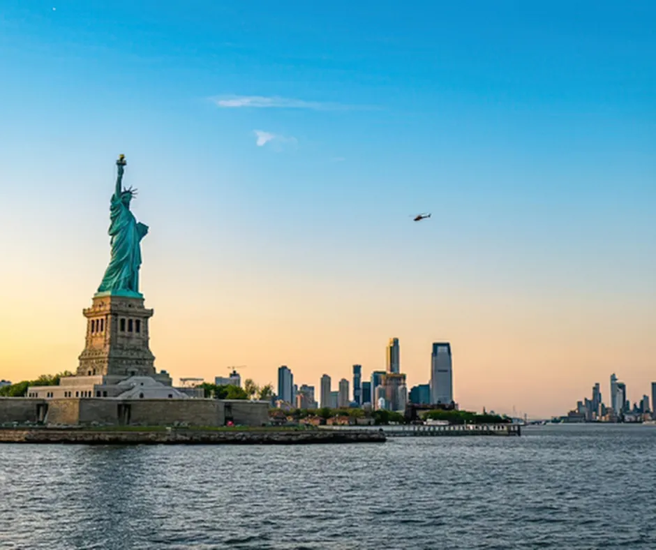 New York – Statua della Libertà Statua della Libertà sul porto di New York con skyline sullo sfondo al tramonto.