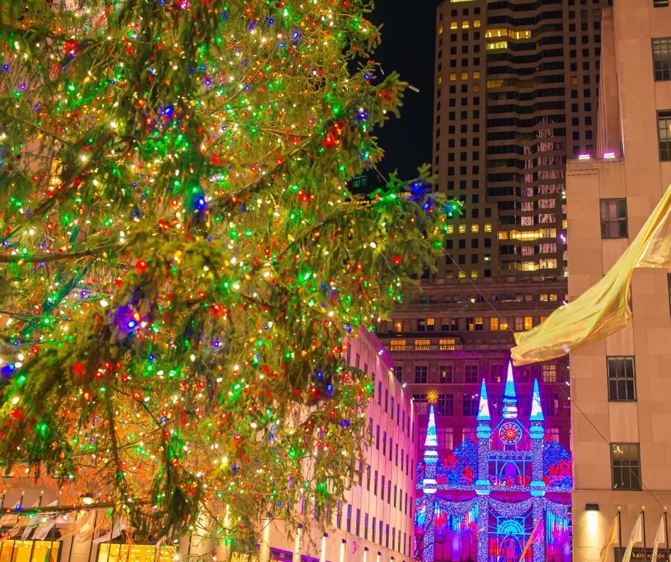New York – Luci e decorazioni natalizie Rami di un grande albero di Natale illuminato con luci multicolori e decorazioni luminose sugli edifici di New York.