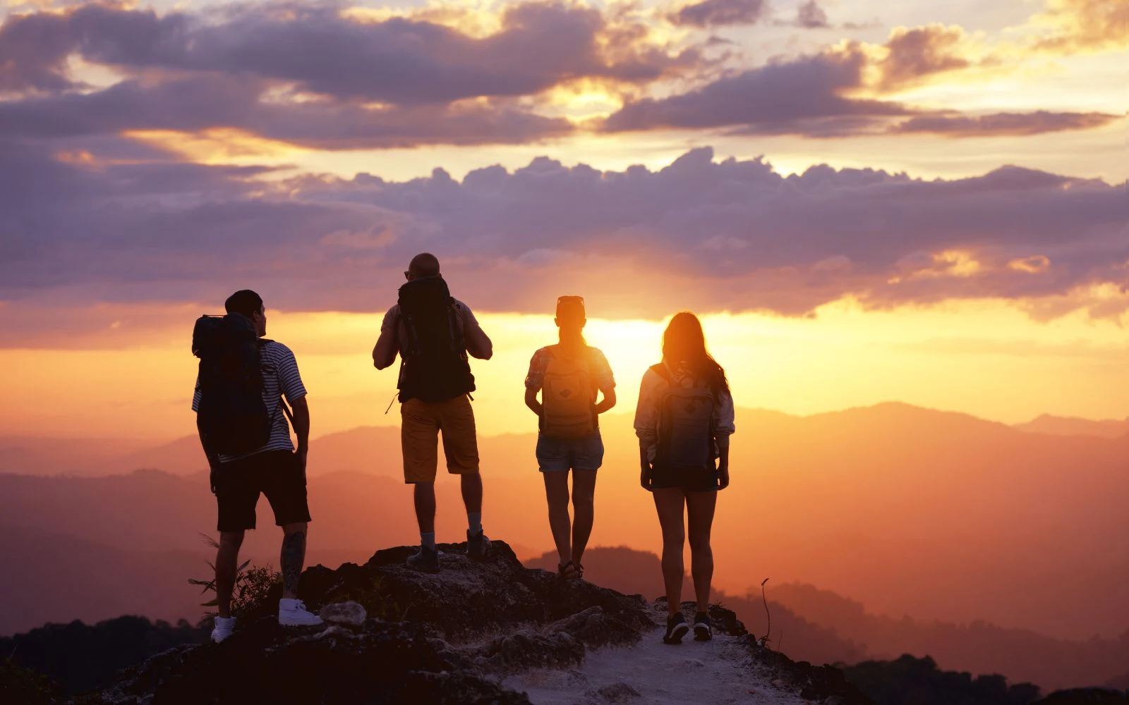 Viaggiatori con zaino osservano il tramonto da una montagna