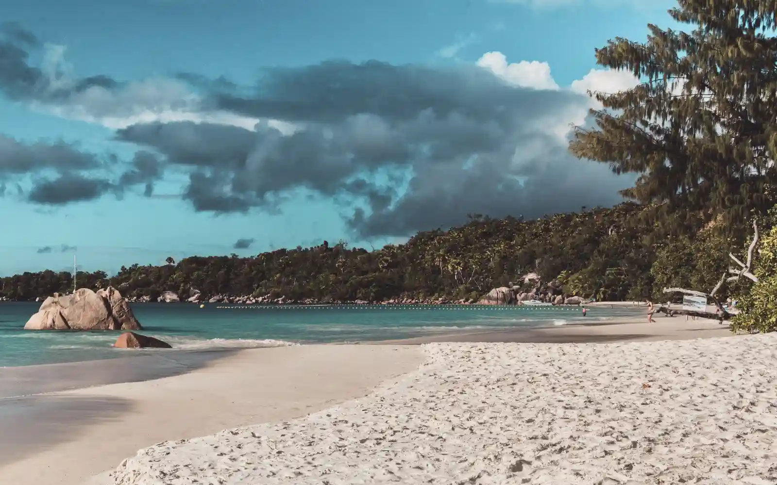 Ampia spiaggia di sabbia bianca alle Seychelles con mare cristallino, rocce di granito e vegetazione lussureggiante
