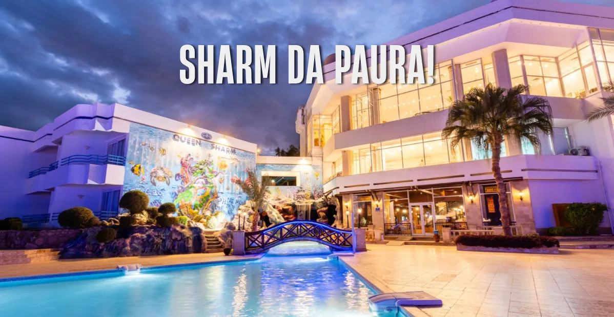 Piscina del resort Queen Beach Sharm al tramonto con edificio illuminato e titolo promozionale “Sharm da paura”.